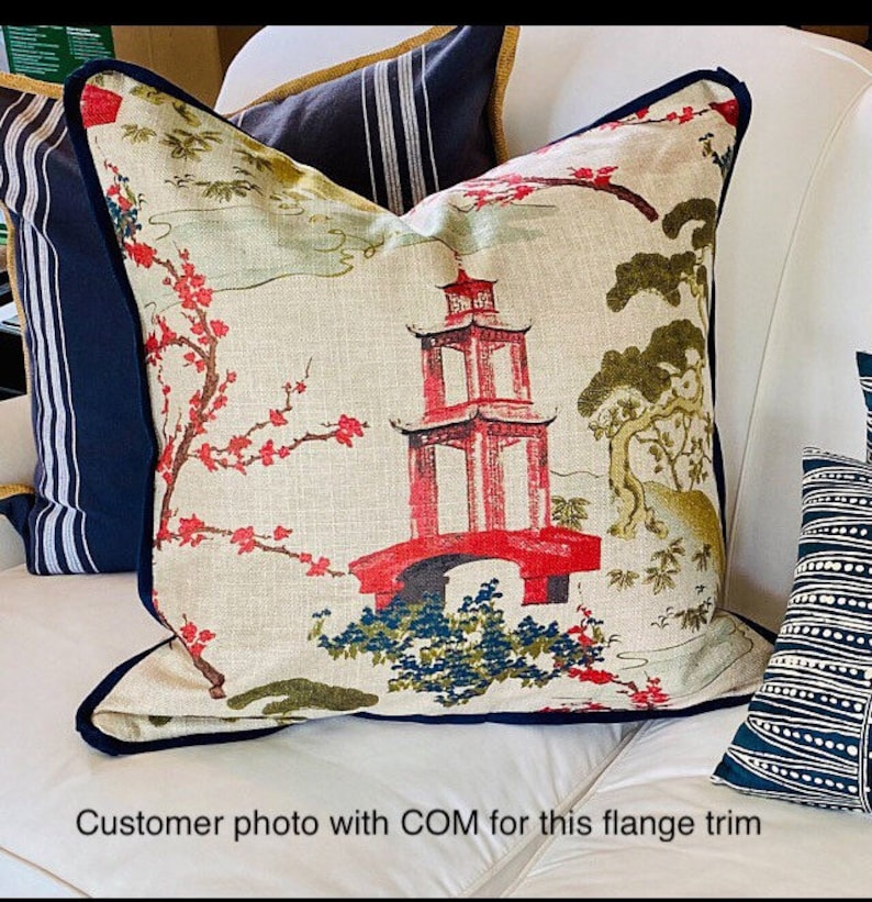 Pode incluir: Uma almofada branca com uma guarni&ccedil;&atilde;o azul marinho de franja apresenta um design asi&aacute;tico colorido com uma pagoda vermelha, flores de cerejeira e &aacute;rvores.