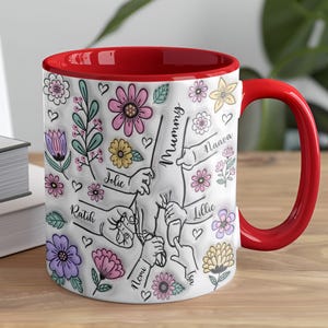 May include: White ceramic mug with a red rim. The mug features a floral design with handprints and the names "Mummy", "Naava", "Jolie", "Ratih", "Lillie", "Nomi", "Isa" and "Isu".