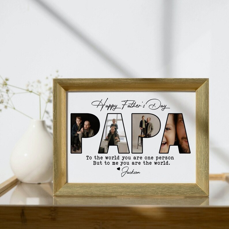 Op de afbeelding: Een ingelijst Vaderdagcadeau met een goudkleurige lijst. Het woord "PAPA" wordt gevormd door foto's van een vader en kind. De tekst luidt "Happy Father's Day" en "Voor de wereld ben je &eacute;&eacute;n persoon, maar voor mij ben je de wereld." Ondertekend "Jackson."