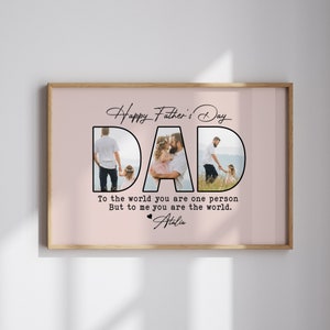 Op de afbeelding: Een ingelijste Vaderdag print met het woord "DAD" in grote, zwarte letters, waarbij elke letter een familiefoto bevat. De print bevat de tekst "Happy Father's Day" en een persoonlijke boodschap, alles tegen een zachtroze achtergrond.