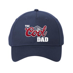 May include: Navy blue baseball cap with the text "The Cool Dad" in a red and white design. The design includes a mountain graphic. A classic, adjustable hat for everyday wear.
