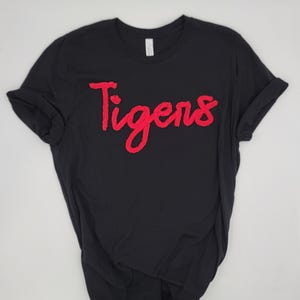 May include: Black t-shirt with a red "Tigers" graphic in a cursive font.