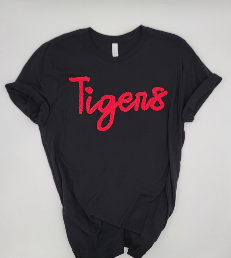 May include: Black t-shirt with a red "Tigers" graphic in a cursive font.