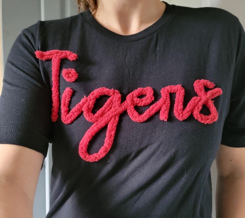 May include: Black t-shirt with a red fuzzy "Tigers" graphic.