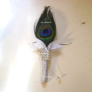Peacock feather boutonniere with silver ribbon and faux rhinestone