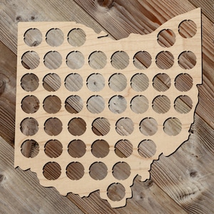 May include: Wooden Ohio state outline with 90 circles for bottle caps. The outline is made of light brown wood and is approximately 12 inches tall.