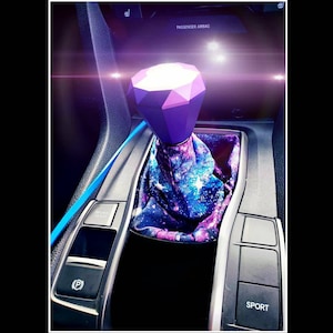 May include: Purple diamond-shaped gear shift knob with a galaxy print gear shift boot. The gear shift is in a car with a "Sport" button and a "Brake Hold" button.