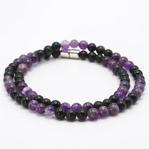 May include: A double-strand necklace with black and purple beads. The necklace has a magnetic clasp.