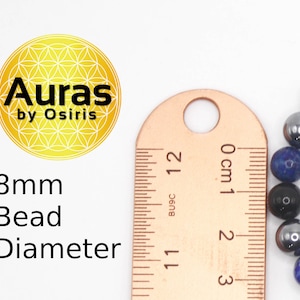 May include: Close-up of a ruler measuring the diameter of a blue, black, and silver beaded bracelet. The beads are 8mm in diameter. The ruler reads 0 cm to 3 cm.