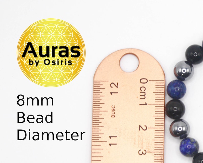 May include: Close-up of a ruler measuring the diameter of a blue, black, and silver beaded bracelet. The beads are 8mm in diameter. The ruler reads 0 cm to 3 cm.