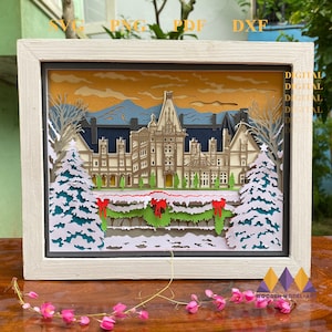 May include: A digital download of a papercraft model of a large white house with a red roof, decorated for Christmas with snow and garlands. The house is set against a backdrop of mountains and a sunset sky.