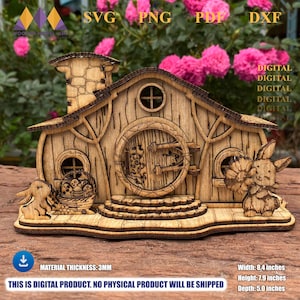 Könnte beinhalten: Ein Holz-Feenhaus mit runder Tür, Fenstern und Schornstein. Das Haus ist mit lasergeschnittenen Details verziert und verfügt über zwei Hasenfiguren. Das Haus ist 21,3 cm breit, 20,1 cm hoch und 12,7 cm tief. Die Materialstärke beträgt 3 mm.