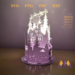 Könnte beinhalten: Eine weiße Papier-Lampe mit einer Winterszene. Die Lampe zeigt ein Haus, Bäume, einen Schneemann und den Weihnachtsmann in seinem Schlitten mit Rentieren, die über dem Haus fliegen. Die Lampe wird von innen beleuchtet und strahlt ein warmes Licht aus.