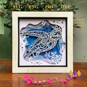 May include: A white frame with a blue and white paper cut-out design of a sea turtle swimming in the ocean. The design includes coral and bubbles. The frame is labeled "SVG PNG PDF DXF" and "DIGITAL DIGITAL DIGITAL DIGITAL DIGITAL".