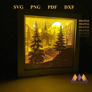 May include: A digital cut file design of a winter scene with a church, trees, a deer, and a full moon. The design is perfect for creating a 3D shadow box or a laser cut project.