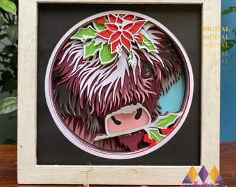 May include: A layered paper art piece of a Highland cow in a white wooden frame. The cow is depicted with shades of burgundy, white, and black, with a poinsettia and holly accents. The top of the frame has the text "SVG PNG PDF DXF".