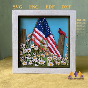 May include: A white frame with a green mat surrounds a papercraft scene of an American flag draped over a wooden fence post with a red cardinal perched on top.  White daisies with yellow centers are in the foreground.  The text "DIGITAL DIGITAL DIGITAL DIGITAL DIGITAL" is in the upper right corner of the image.