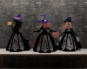 Może przedstawiać: Trzy dekoracje na Halloween z wiedzmami. Każda wiedźma ma na sobie czarną suknię i fioletowy kapelusz. Jedna wiedźma trzyma świecącą kulę, druga miotłę i dynię, a trzecia dynię i ma czarnego kota. Suknie mają dekoracyjny, wycięty wzór.