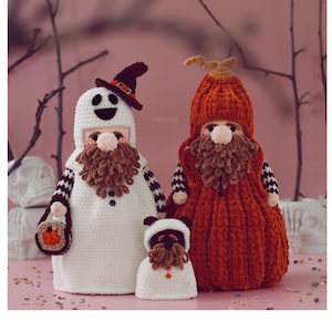May include: Three handmade Halloween-themed gnome figures. One is a ghost with a black hat, another is a pumpkin, and the smallest is a gnome. All have brown beards and are made of yarn.
