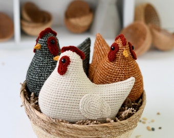 May include: Three crocheted chickens in a woven basket. The chickens are brown, white, and black with red and yellow accents.