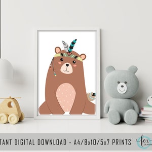 May include: A framed print featuring a cartoon bear with a Native American headdress. The bear is brown with a light pink belly and is sitting down. The headdress has a blue and black feather. The print is displayed on a white surface.