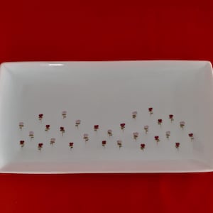 Peut inclure: Un plat de service rectangulaire blanc avec un motif décoratif de petites fleurs roses et rouges.