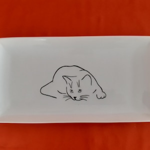 Peut inclure: Un plat de service rectangulaire en céramique blanche avec un dessin au trait noir d'un chat enroulé sur le plat.