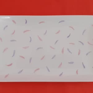 Peut inclure: Un plat de service rectangulaire blanc avec un motif décoratif de plumes roses et violettes.