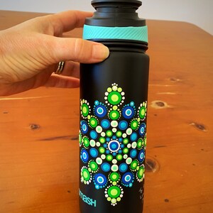 May include: A black water bottle with a teal lid and a hand-painted mandala design in shades of green, blue, and white.