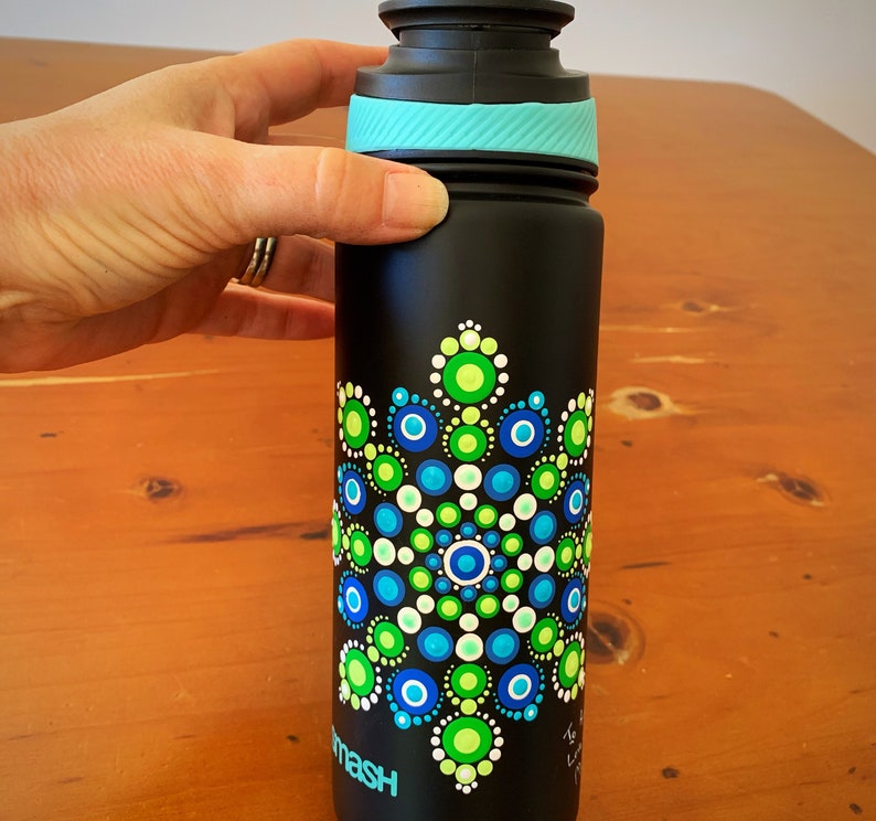 May include: A black water bottle with a teal lid and a hand-painted mandala design in shades of green, blue, and white.