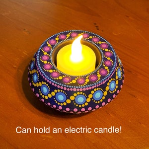 May include: A teal blue candle holder with a mandala design in pink, yellow, and blue. The holder has a small opening in the center to hold a tea light or electric candle. Can hold an electric candle!