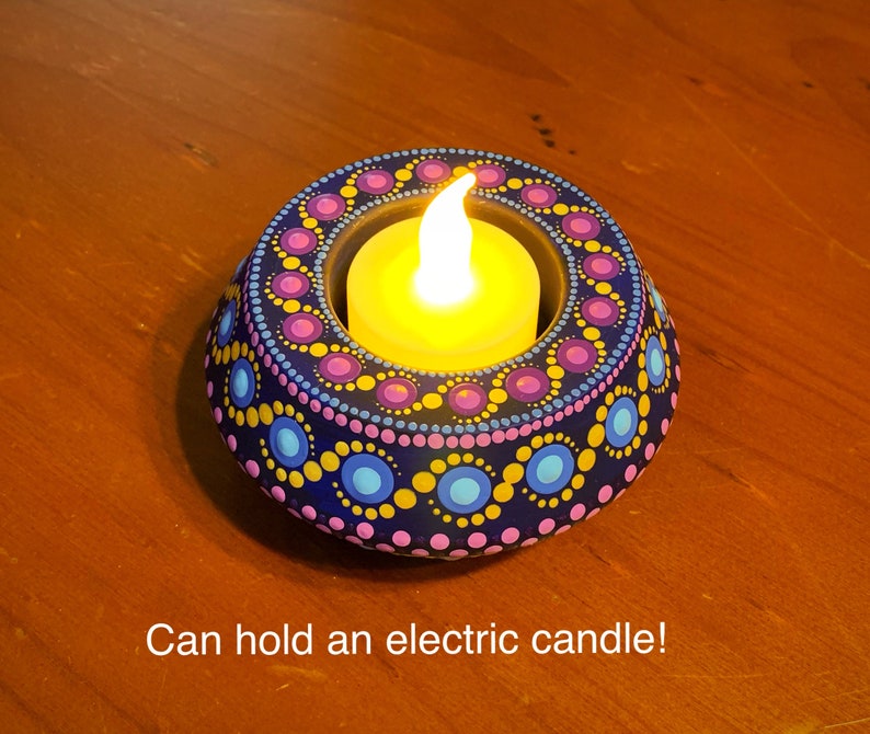 May include: A teal blue candle holder with a mandala design in pink, yellow, and blue. The holder has a small opening in the center to hold a tea light or electric candle. Can hold an electric candle!