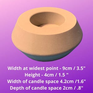 May include: A light brown concrete candle holder with a round opening for a candle. The holder is 3.5 inches wide and 1.5 inches tall. The candle space is 1.6 inches wide and .8 inches deep.