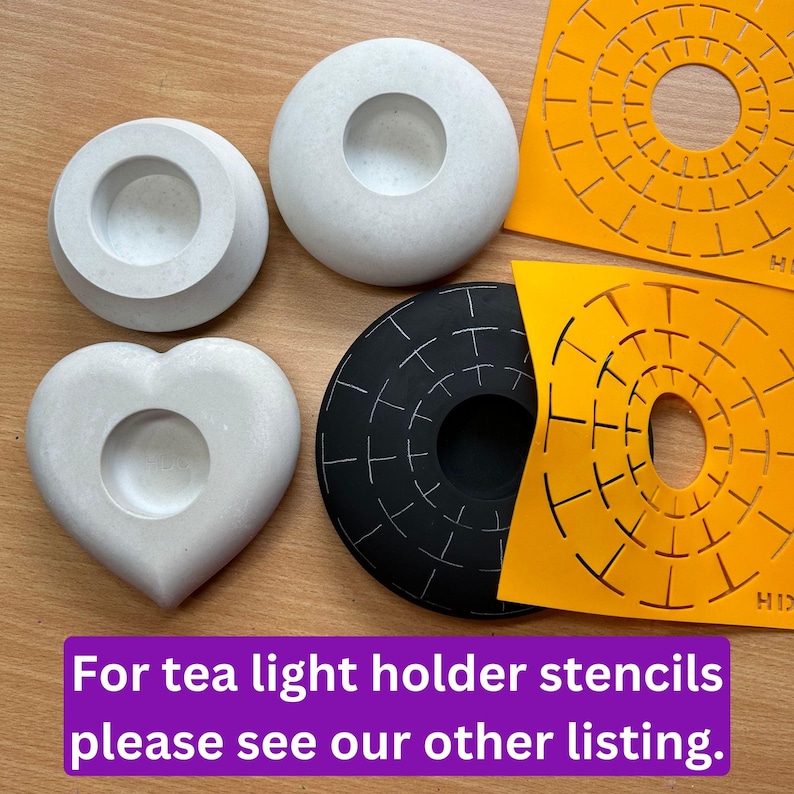 May include: Four concrete candle holders in different shapes: a round one, a heart-shaped one, and two round ones with a raised rim. The round candle holders are white, the heart-shaped one is gray, and the round ones with a raised rim are white. There are two orange stencils with a circular design, one black and one orange.