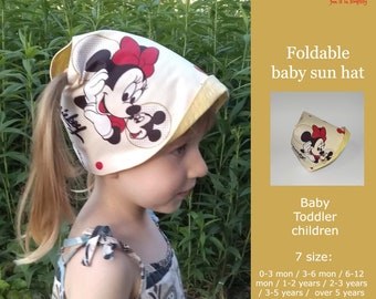 May include: A yellow and white foldable baby sun hat with a Mickey Mouse and Minnie Mouse print. The hat is designed for babies and toddlers and comes in seven sizes: 0-3 months, 3-6 months, 6-12 months, 1-2 years, 2-3 years, 3-5 years, and over 5 years old.