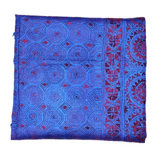 May include: A blue and burgundy fabric with a repeating geometric pattern. The fabric has a textured surface and is woven with a fine thread.