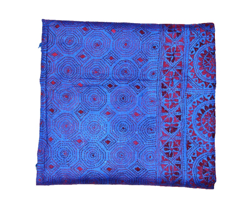 May include: A blue and burgundy fabric with a repeating geometric pattern. The fabric has a textured surface and is woven with a fine thread.