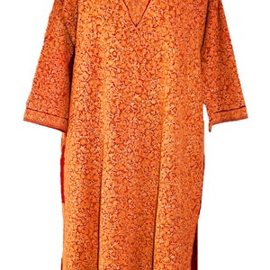 May include: A long, orange, embroidered tunic with a red neckline and trim. The tunic is made of a soft, lightweight fabric and features a floral pattern.