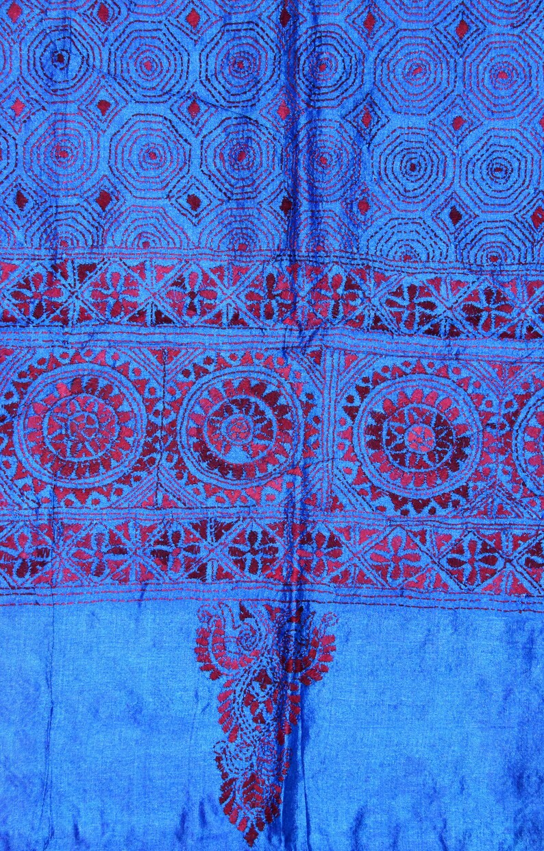 May include: A blue fabric with a red embroidered design. The design features intricate patterns of circles, flowers, and geometric shapes.