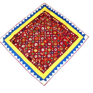 Könnte beinhalten: Ein rotes quadratisches Textil mit einem bunten geometrischen Muster, umgeben von einem gelben Rand und einem blau-weißen gewellten Rand.