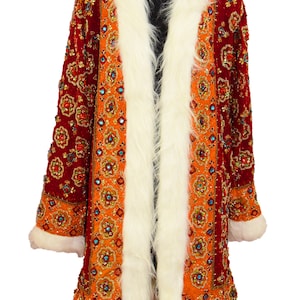 May include: A long, red and orange velvet coat with a white fur collar and cuffs. The coat is heavily embellished with sequins and beads in a floral pattern.
