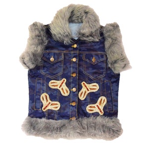 Könnte beinhalten: Eine blaue Jeansweste mit Camouflage-Muster und Kunstfellbesatz. Die Weste hat mehrere goldene und rote Verzierungen.