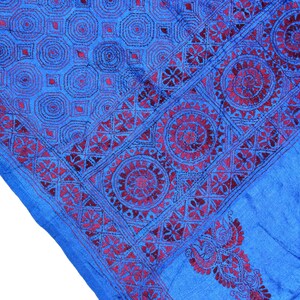 May include: A blue silk scarf with a burgundy embroidered border featuring intricate geometric patterns. The design includes circles, squares, and triangles.