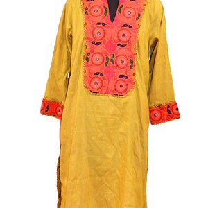 May include: A yellow long-sleeved tunic with a pink and blue embroidered neckline and cuffs. The embroidery features a circular pattern with small mirrors.