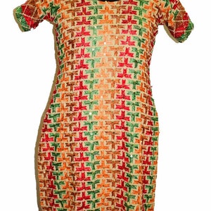 Peut inclure: Une tunique beige brodée avec un motif géométrique dans des tons de rouge, vert et orange. La tunique a un col rond et des manches courtes.