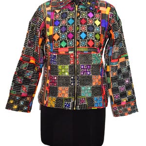 Könnte beinhalten: Bunte Patchwork-Jacke mit schwarzer Basis und lebendigen Quadraten in Orange, Gelb, Grün, Blau und Pink. Die Jacke hat einen Reißverschluss und lange Ärmel. Das Design umfasst geometrische Muster und Spiegelakzente.