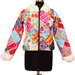 以下が含まれることがあります： 白いフェイクファーの襟とカフスが付いたカラフルなパッチワークジャケット。ジャケットは、花柄、幾何学模様、ペイズリー柄など、さまざまな生地とパターンで作られています。