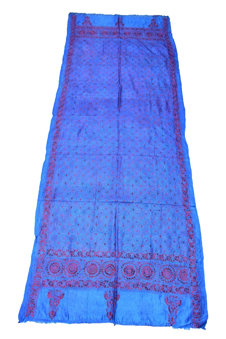 May include: A blue silk shawl with intricate red embroidery. The shawl features a repeating pattern of circles and floral motifs.
