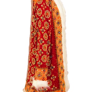 May include: A long, red and orange coat with a white fur collar and trim. The coat is covered in intricate beading and sequins.