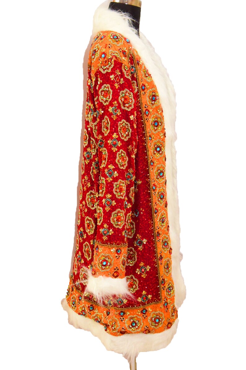 May include: A long, red and orange coat with a white fur collar and trim. The coat is covered in intricate beading and sequins.